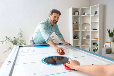 Genç adam ve kız arkadaşı evde hokey oynuyorlar.