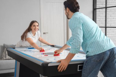 Kocasıyla evde hokey oynayan genç bir kadın.