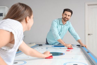 Genç adam ve kız arkadaşı evde hokey oynuyorlar.