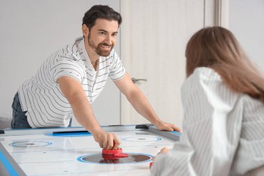 Genç adam ve kız arkadaşı evde hokey oynuyorlar.