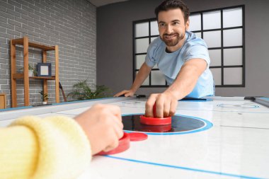 Genç adam evde karısıyla hokey oynuyor.