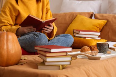 Evde tepside kitap okuyan bir kadın.