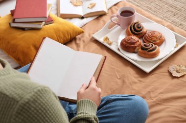 Boş kitabı olan bir kadın evde, yatakta oturuyor. Kapalı.