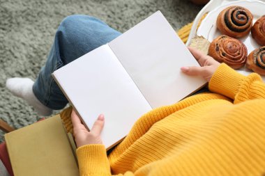 Boş kitapları ve kalçaları olan bir kadın evdeki kanepede oturuyor.