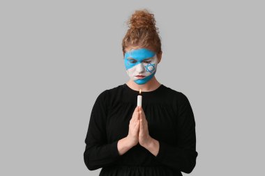 Yüzünde İsrail 'in boyalı bayrağı olan genç bir kadın ve yanan bir mumla arka planda dua ediyor. Uluslararası Soykırım Anma Günü