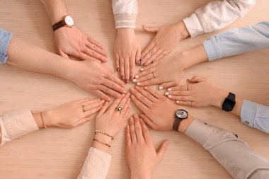 Bir grup insan ellerini masanın üstüne koyuyor.