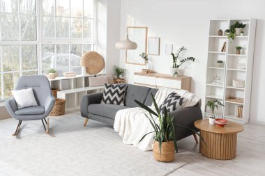 Oturma odasının içinde kanepe, sallanan koltuk ve bitkiler var.