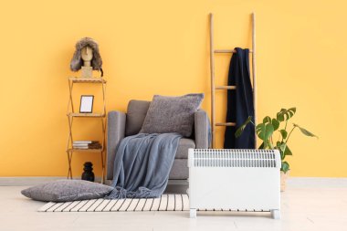 Modern konveksiyon ısıtıcısı ve gri koltuğu olan şık bir oturma odası.