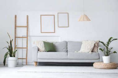 Gri kanepe, merdiven ve boş çerçevelerle aydınlık oturma odasının içinde.