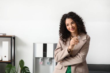 Ofisteki soğutucudan bir bardak su alan güzel bir iş kadını.