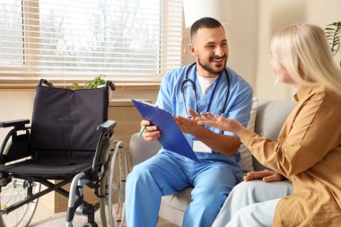 Erkek doktor evde olgun bir kadınla çalışıyor.