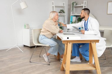 Erkek doktor klinikte olgun bir kadınla çalışıyor.