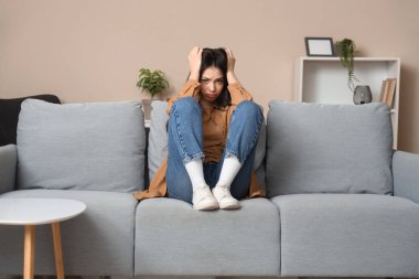 Kanepede oturan endişeli genç kadının portresi.