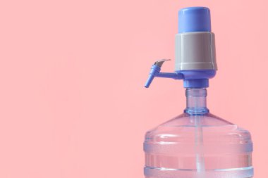 Pembe arka planda pompalı bir şişe temiz su, yakın plan.
