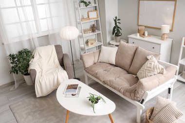 Aydınlık oturma odasının içinde koltuk, lamba ve kanepe