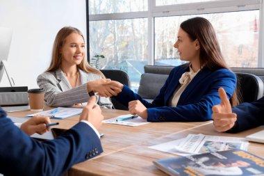 İş kadınları konferans odasında el sıkışıyor.