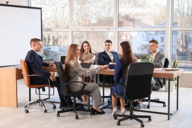 İş kadınları konferans odasında el sıkışıyor.