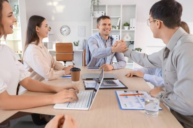 Erkek meslektaşlar ofiste el sıkışıyor.