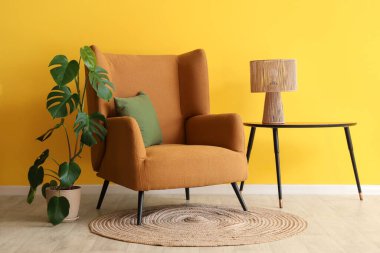 Kahve masasında rahat kahverengi koltuğu, çiçekleri ve lambası olan şık bir oturma odası.