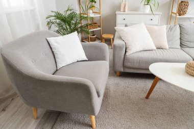 Rahat gri koltuğu, kanepesi ve sehpası olan şık bir oturma odası.