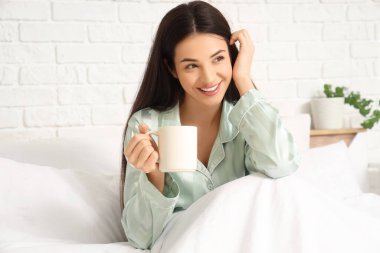 güzel bir genç kadın yatakta çay ile