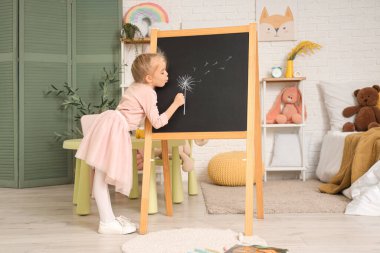 Evdeki yazı tahtasına üfleme topu çizen tatlı küçük kız.