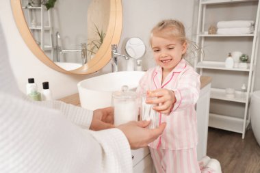 Banyoda annesinden pamuk tomurcukları alan tatlı küçük bir kız.