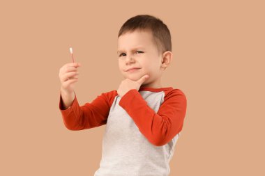 Bej arka planda pamuk tomurcuğu olan düşünceli küçük bir çocuk.