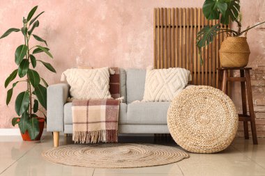 Oturma odasının iç tarafında rahat bir kanepe, puf ve bitkiler var.