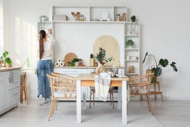 Mutfakta rafın yanında genç bir kadın var.