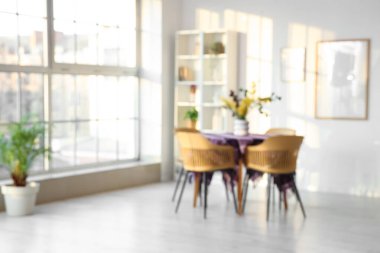 Yemek odasının içinde güzel çiçekler ve şık mor kumaşlar pencerenin yanındaki masada bulanık bir görüntü.