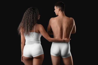 Siyah arka planda şık iç çamaşırlı genç bir çift.