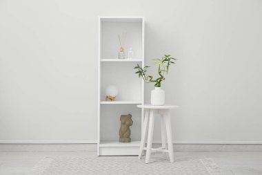 Kahve masasında bambu saplı vazo ve beyaz duvarın yanında raf ünitesi.