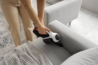 Evde elektrikli süpürge temizleyen genç bir kadın var.