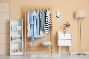 Giysi askısı, raf ünitesi ve katlama ekranı olan şık bir soyunma odası.