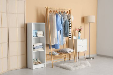 Giysi askısı, raf ünitesi ve katlama ekranı olan şık bir soyunma odası.