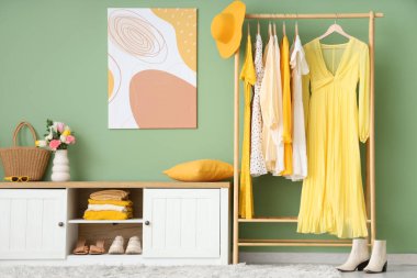 Modern giyinme odasının içinde şık kadın kıyafetleri ve bahar çiçekleri var.