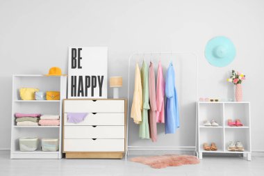 Kadın kıyafetleri, ayakkabıları ve posterleri olan modern bir soyunma odası.