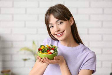 Mutfakta taze sebze salatası olan genç bir kadın.