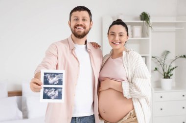 Yatak odasında ultrason görüntüsü olan mutlu hamile çift.