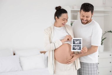 Yatak odasında ultrason görüntüsü olan mutlu hamile çift.