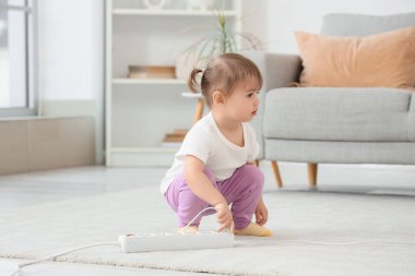 Evdeki uzatma kablosuna takılan tatlı küçük kız. Çocuk tehlikede.