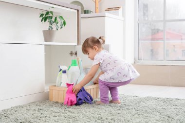 Mutfaktaki çekmeceden temizlik malzemeleriyle dolu kutuyu alan tatlı küçük kız. Tehlikedeki çocuk