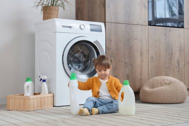 Evde yerde çamaşır deterjanı olan sevimli küçük bir kız. Çocuk tehlikede.