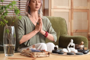 Kadın kanepede otururken meditasyon yapıyor.