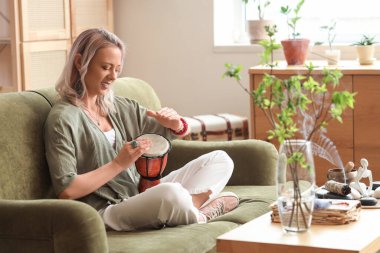 Kadın davul çalıyor ve evde meditasyon yapıyor.