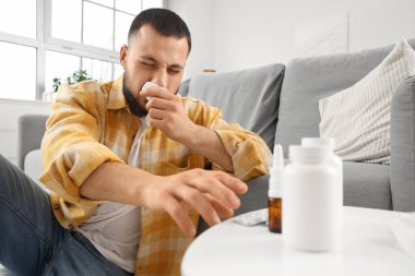 Evdeki masadan burun damlası alan dokuları olan hasta genç bir adam.