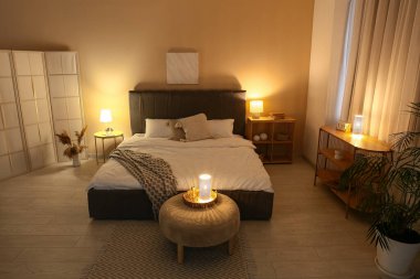 Rahat gri yataklı, yumuşak puf ve geceleri parlayan lambalar olan şık bir yatak odası.