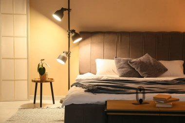 Rahat gri yataklı ve geceleri parlayan lambasıyla yatak odasının şık bir iç mekanı.