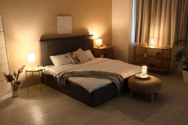 Rahat gri yataklı, yumuşak puf ve geceleri parlayan lambalar olan şık bir yatak odası.